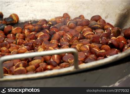 Chestnuts roasting in a pan at street vendor&acute;s stand