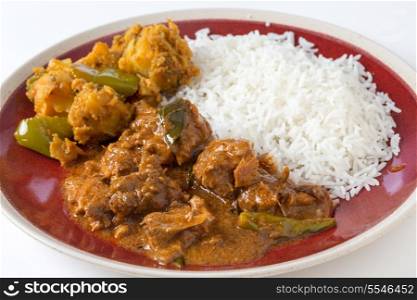 Chettinadu traditional Indian chicken bone-in curry, served with white rice and an aloo capsicum potato and bell pepper vegetable dish.