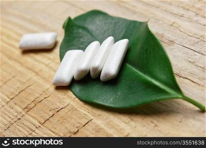 chewing gum and green leaf on a wooden background