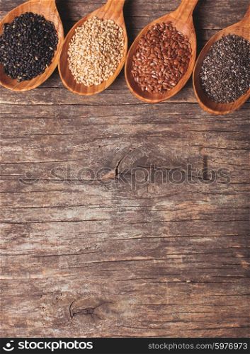 Chia and flax seeds, white and black sesame in wooden spoons
