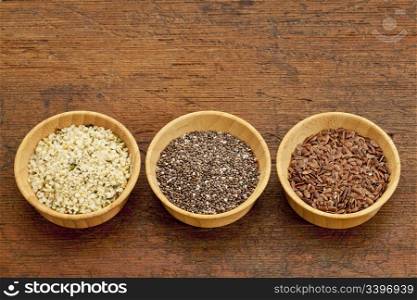 chia, flax and hemp healthy seeds in small wooden bowls