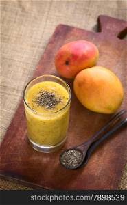 Chia seed (lat. Salvia hispanica) and mango juice photographed on wood with natural light. Chia seeds are considered a superfood containing proteins, omega fats, minerals and antioxidants (Selective Focus, Focus on the chia seeds on the juice)