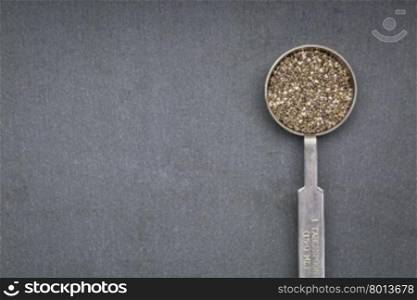 chia seed on metal measuring tablespoon against slate sone with a copy space