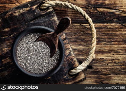 Chia seeds in a wooden bowl on a wooden rustic background