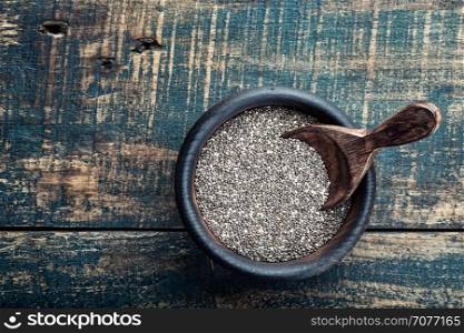Chia seeds in a wooden bowl on a wooden rustic background