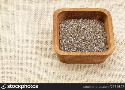 chia seeds in square wooden bowl against burlap canvas
