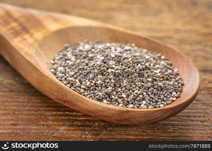 chia seeds on a wooden spoon against a grunge wood, selective focus