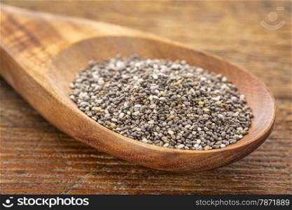 chia seeds on a wooden spoon against a grunge wood, selective focus