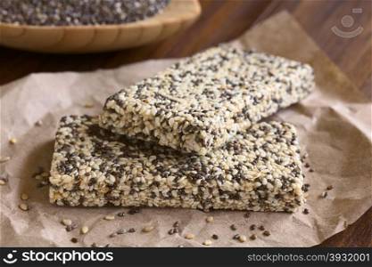Chia sesame honey granola bars, photographed with natural light. Chia (lat. Salvia hispanica) is considered a superfood containing protein, omega fat, minerals, antioxidants (Selective Focus, Focus on the front edge of the granola bars)