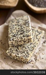 Chia sesame honey granola bars, photographed with natural light. Chia (lat. Salvia hispanica) is considered a superfood containing protein, omega fat, minerals, antioxidants (Selective Focus, Focus on the front edge of the upper bar)