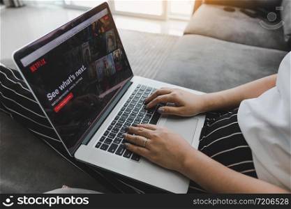CHIANG MAI ,THAILAND - March 31, 2018 : Woman sitting sofa using laptop and watching Netflix website.