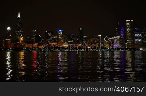 Chicago downtown cityscape reflected on the Michigan lake at nighttime. Awesome Chicago financial city center skyline at night. Colorful illuminated skyscrapers of Chicago.