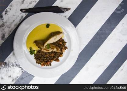 Chichen with≤ntils, bacon and corn sauce in the plate on the tab≤