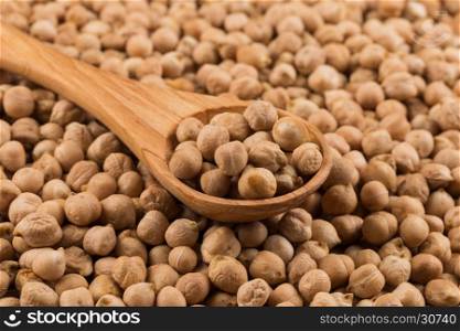 Chick-pea in wooden spoon. Beans as a background. Close-up.