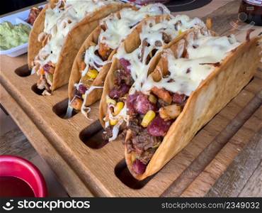 Chicken and cheddar cheese tacos on a taco board with sauces on the side