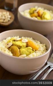 Chicken and dried apricot stew, seasoned with turmeric, cinnamon and honey, served on couscous with roasted almonds, photographed with natural light (Selective Focus, Focus in the middle of the dish)