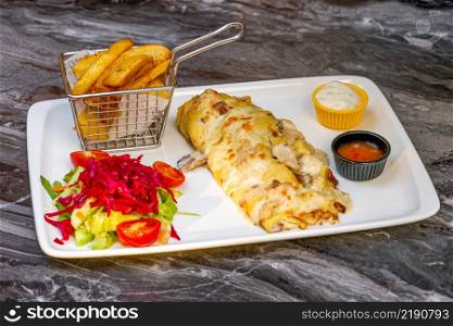 Chicken and mushroom pancakes or crepes with salad and french fries on a white plate