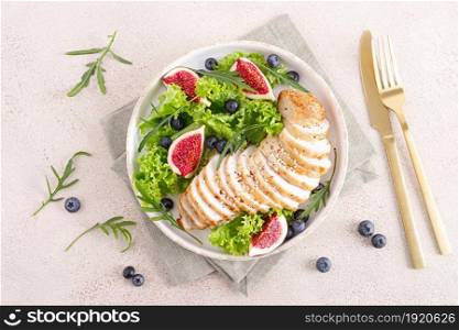 Chicken breast baked and fresh salad of lettuce, arugula, blueberry and figs. Healthy diet food. Top view.