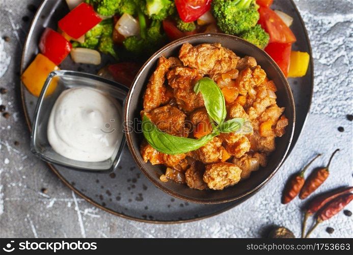 Chicken breast in creamy garlic sauce in bowl and baked vegetables
