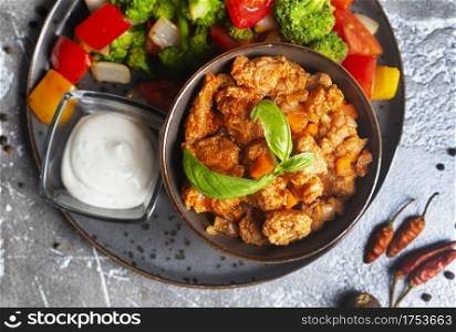 Chicken breast in creamy garlic sauce in bowl and baked vegetables