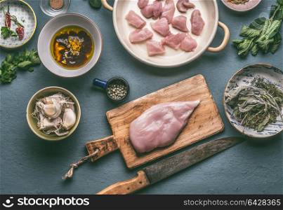 Chicken breast on wooden cutting board with knife , kitchen table background with ingredients in bowls and honey mustard marinate, top view. Dieting cooking eating and healthy food concept