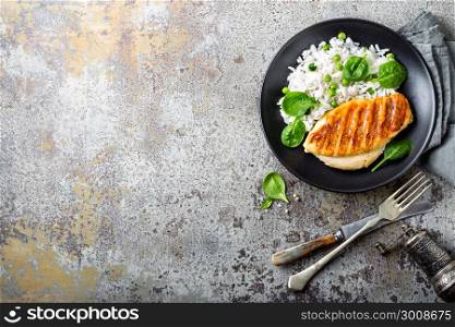 Chicken breast or fillet, poultry meat grilled and boiled white rice with green peas and fresh spinach leaves. Healthy diet menu for lunch