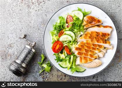 Chicken breast or fillet, poultry meat grilled and fresh vegetable salad of tomato, cucumber and lettuce. Healthy diet menu for lunch