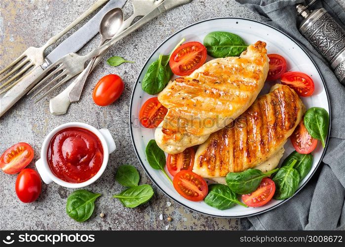 Chicken breast or fillet, poultry meat grilled and fresh vegetable salad of tomato and spinach. Healthy diet menu for lunch