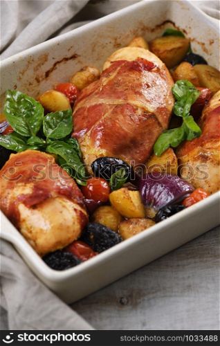 Chicken breast stuffed with goat cheese with spinach, wrapped in prosciutto, with slices of baked potatoes, tomatoes, and dried prunes.