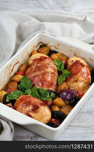 Chicken breast stuffed with goat cheese with spinach, wrapped in prosciutto, with slices of baked potatoes, tomatoes, and dried prunes.