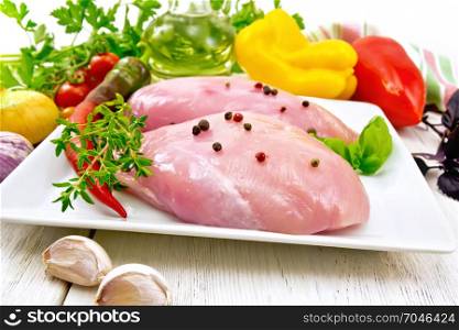 Chicken breast with hot pepper and thyme in a plate, napkin, parsley and basil, onion, garlic and vegetables against a light wooden board