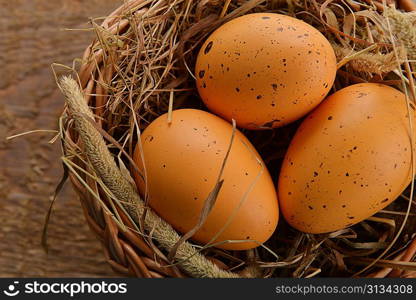 chicken brown eggs in wicker basket on wooden background