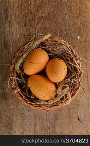 chicken brown eggs in wicker basket on wooden background