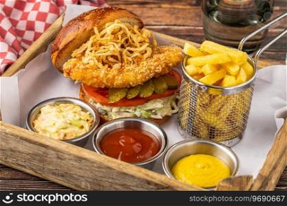 Chicken burger served with french fries and sauces in a wooden case