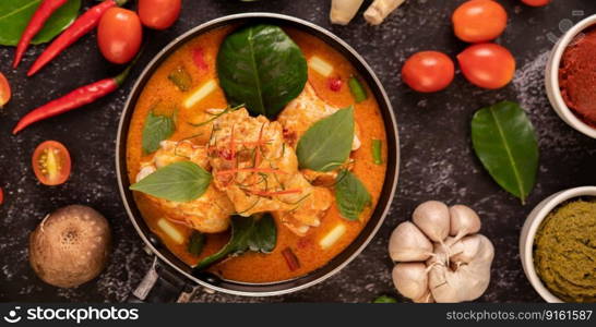 Chicken curry in a pan with lemongrass, kaffir lime leaves, tomatoes, lemon, and garlic