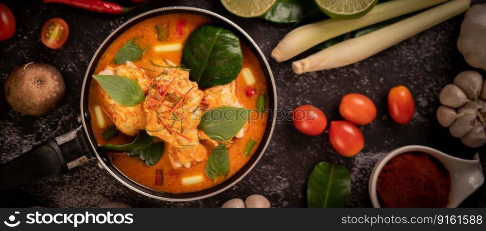 Chicken curry in a pan with lemongrass, kaffir lime leaves, tomatoes, lemon, and garlic