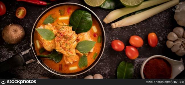 Chicken curry in a pan with lemongrass, kaffir lime leaves, tomatoes, lemon, and garlic
