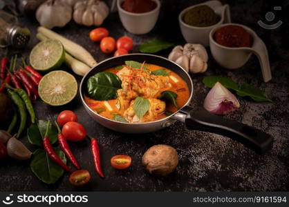 Chicken curry in a pan with lemongrass, kaffir lime leaves, tomatoes, lemon, and garlic