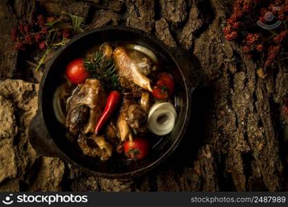 chicken dish with vegetables in a frying pan on the background of tree bark. dish on a tree bark
