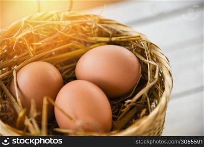 Chicken eggs in basket nest on white wooden background