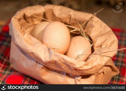 Chicken eggs of brown color lie in a paper bag