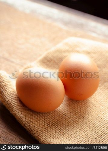 Chicken eggs on sackcloth on wooden tab≤