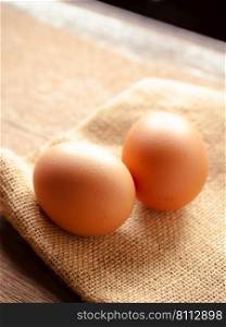 Chicken eggs on sackcloth on wooden tab≤