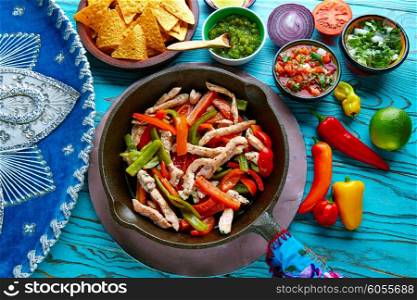 chicken fajitas in a pan with sauces chili and sides Mexican food