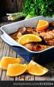 Chicken feet cooked with juicy oranges in the baking dish. Baked chicken with orange
