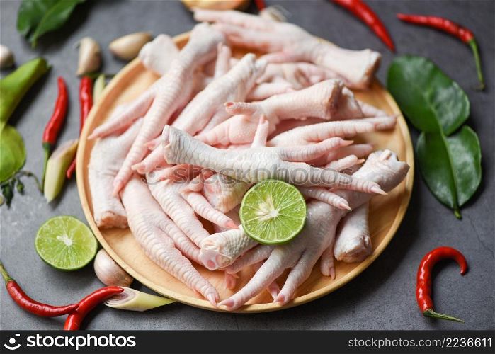 chicken feet on wooden plate with herbs and spices lemon chili garlic kaffir lime leaves, Fresh raw chicken feet for cooked food soup on the dark table kitchen background