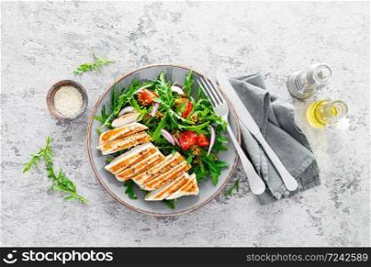 Chicken fillet salad with fresh vegetables and arugula. Fresh vegetable salad of arugula, tomatoes, onion and grilled chicken breast.