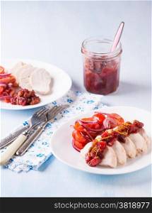 Chicken fillet with cranberry relish and tomato salad, light blue background