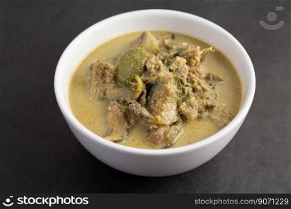Chicken green curry in a white cup on the cement ground.