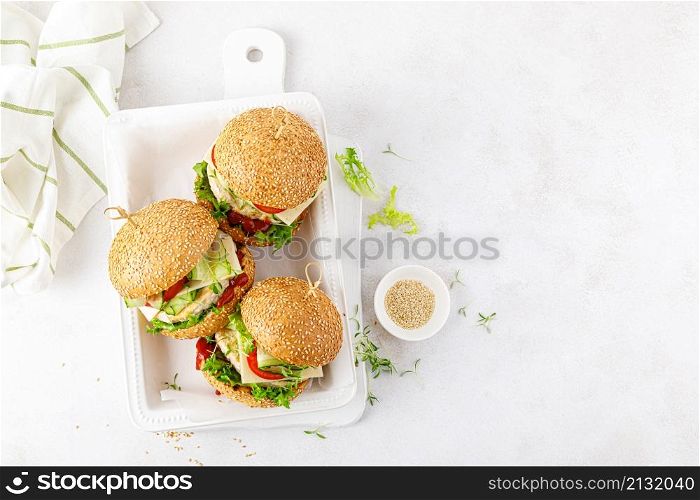 Chicken hamburgers, sandwich with chicken burger, cheese, tomato, cucumber, fresh lettuce, microgreen and ketchup on white background. Top view.